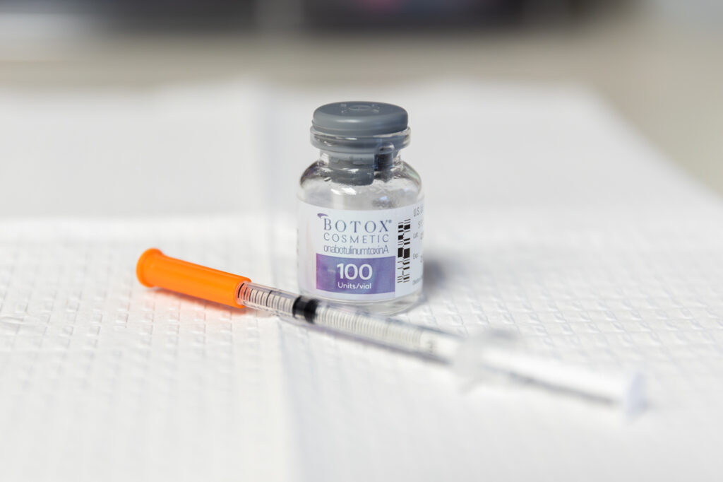 Bottle of Botox and injection needle sitting on a towel